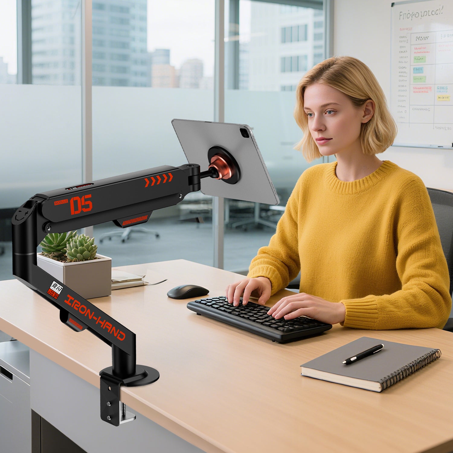 黄色のカーディガンを身につけた女性が、タブレットを使用しているオフィス風景。ブラックのモニターアームとデスク。